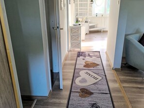 Een hal met een vloerkleed waarop een ontwerp van een huis en het woord 'HOME' staat.
