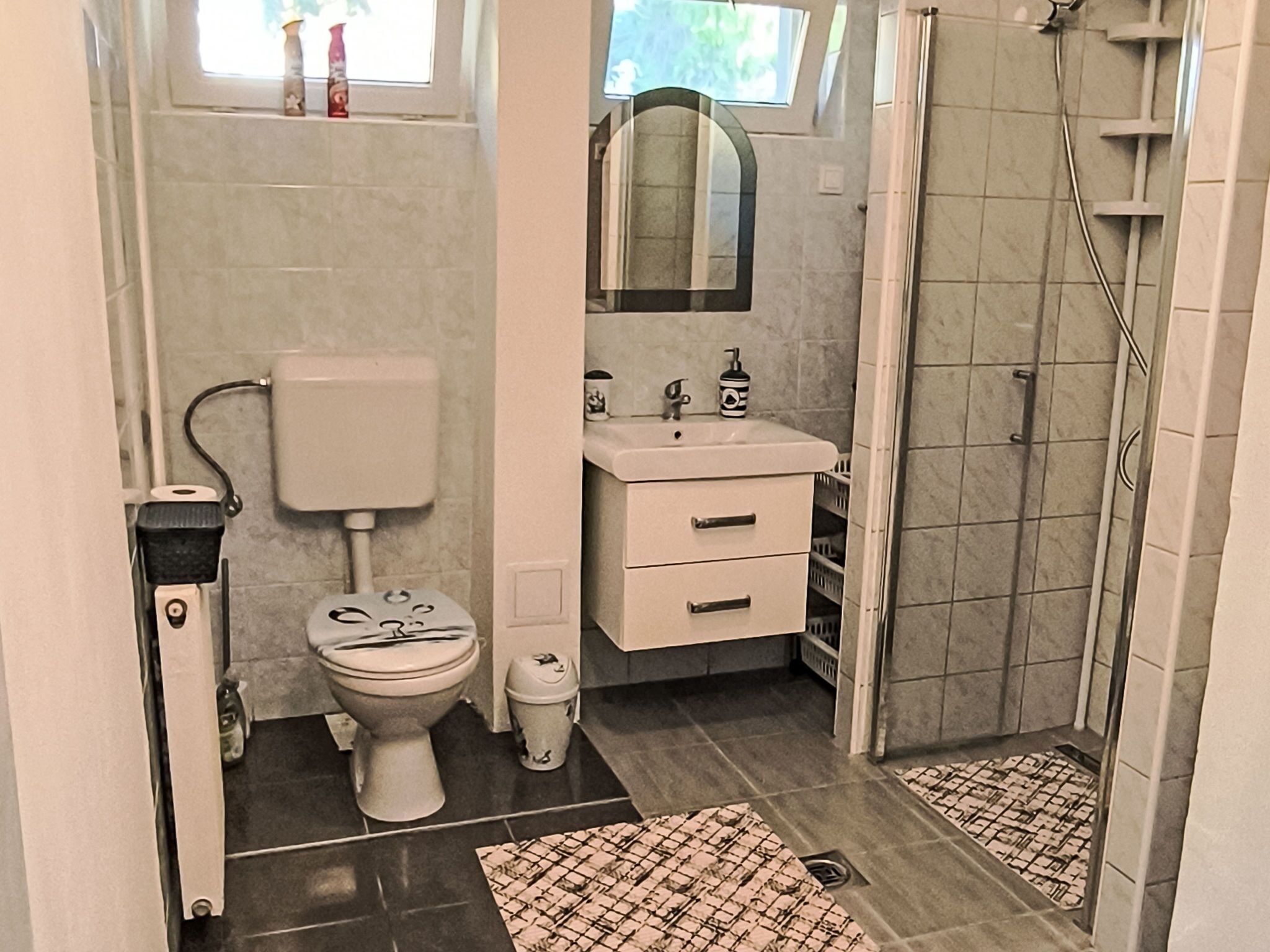 Un baño con inodoro, lavamanos, espejo y ducha.