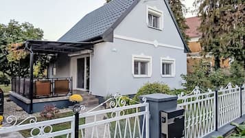 A two-story house with a grey exterior, a covered porch, and a white fence.