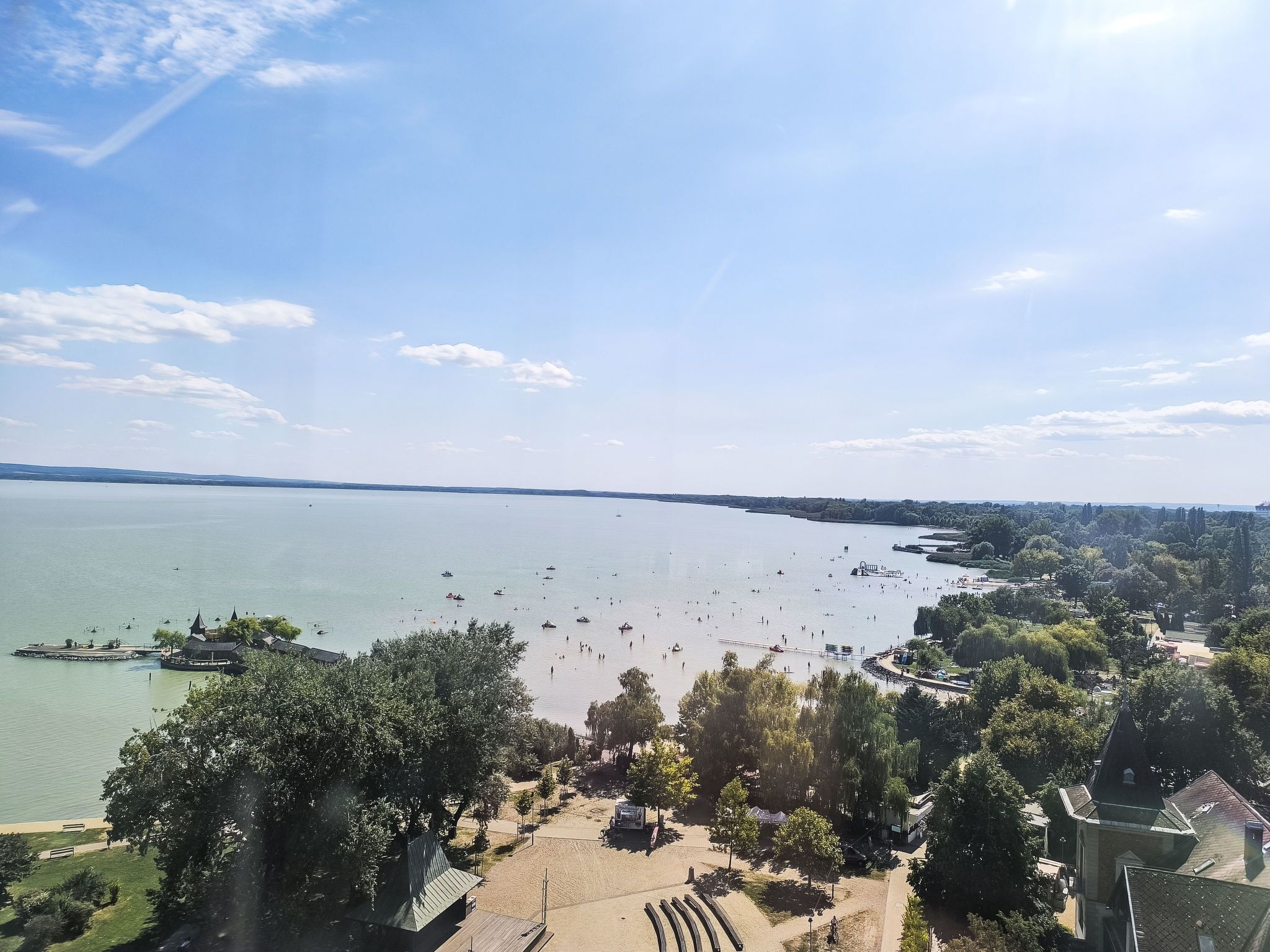 Vista de un lago con un muelle, barcos y una zona de parque.