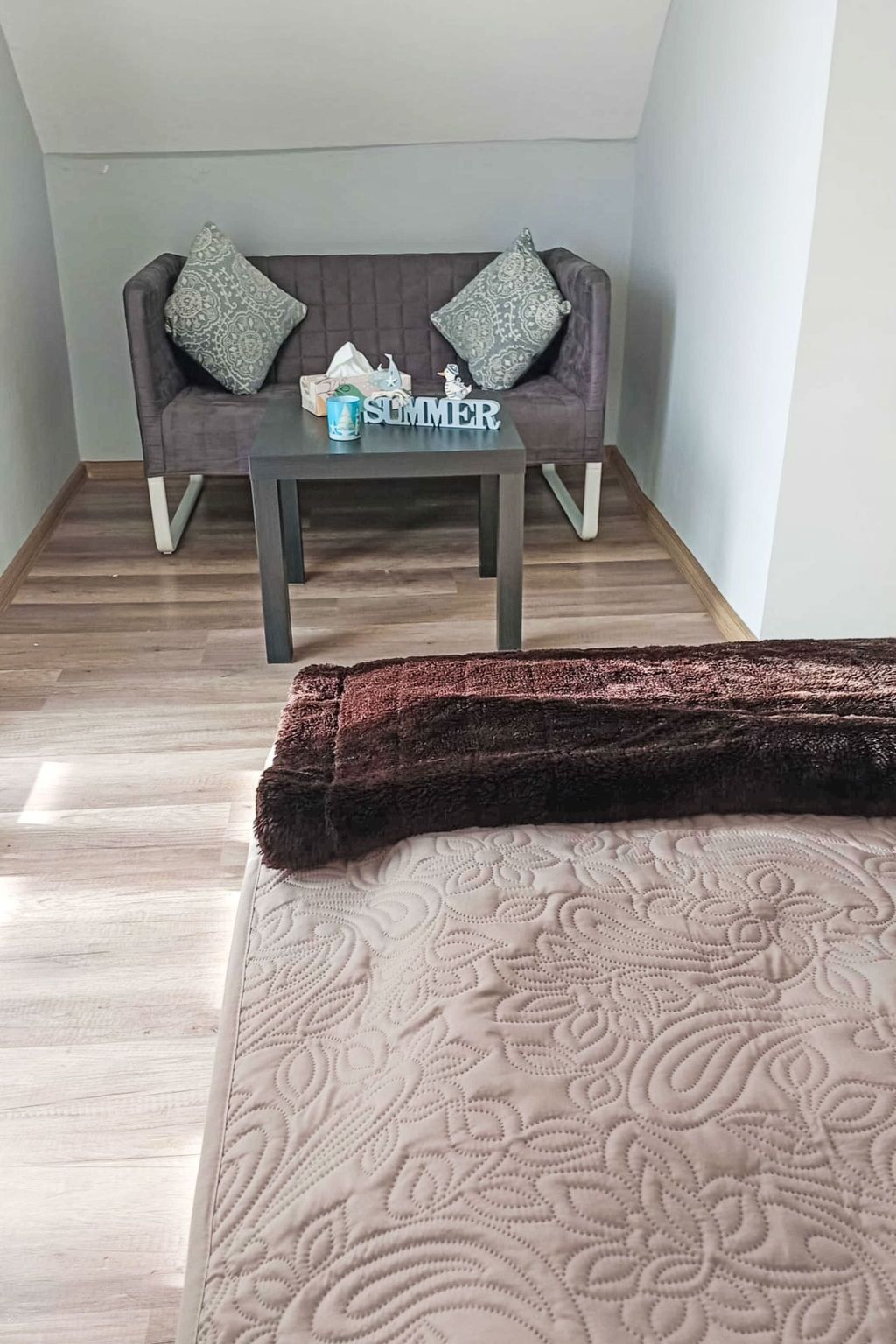 A room with a bed, a sofa, a coffee table, and a rug.