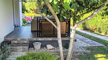 Eine Terrasse mit einem kleinen Baum, einer Sitzgelegenheit mit Tisch und Stühlen sowie einem Blumentopf.