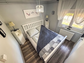 A bedroom with a bed, bedside tables, a lamp, a radiator, a window with curtains, and a wall-mounted picture. - Babaház by Interhome (Balatonmariafurdo)