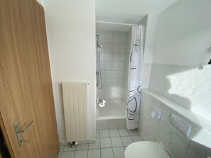 A bathroom with a bathtub, a shower, and a toilet. - Ferienwohnungen JHS, (Seewis), by Interhome (Seewis im Prättigau)
