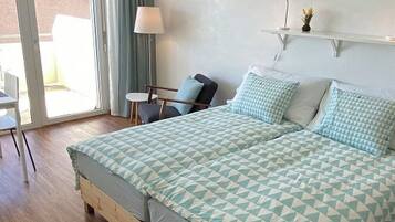 Ein Schlafzimmer mit Bett, Sessel, Schreibtisch und Lampe.