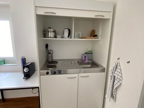 Una kitchenette compacta con estufa, pileta y estanterías.