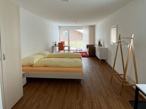Ett hotellrum med en säng, ett skrivbord, en stol, ett litet bord och en tavla på väggen.