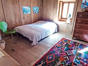 Une pièce comprenant un lit, une chaise, une commode et une fenêtre.