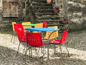 A set of outdoor dining chairs and a table arranged on a cobblestone surface. - Casa Rederer by Interhome (Bondo)