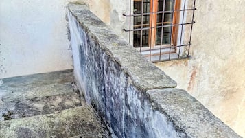 Eine Betonstairtreppe mit Metallgeländer, die zu einem Fenster mit Holzgitter führt.