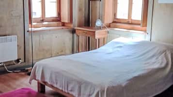 Ein Zimmer mit einem Bett, einem Fenster, einem Spiegel und einer Heizung.