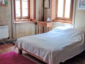 A room with a bed, a window, a mirror, and a radiator.
