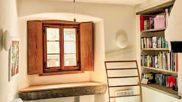 Ein Zimmer mit einer eingebauten Sitzbank, einem Bücherregal und einem Fenster mit Holzläden.