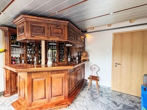 A bar area with wooden cabinetry, a small stool, and a variety of bottles and glasses. - Köbihaus am Sagibach by Interhome (Alpnach)