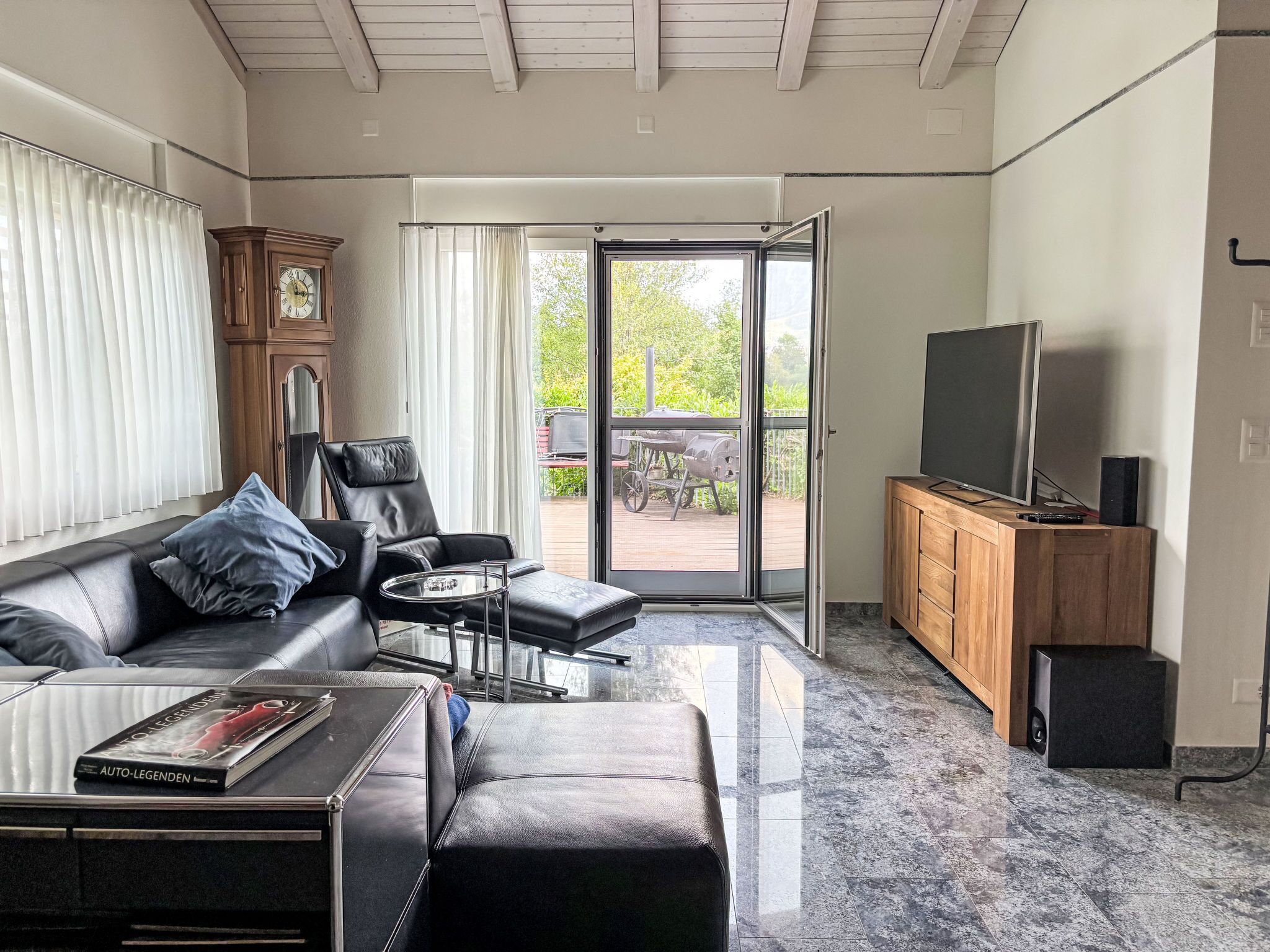Una sala de estar moderna con un sofá de cuero, una mesa de centro, un televisor y un mueble de madera.
