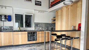 Eine moderne Küche mit Holzschränken, einem Einbauofen und einer Bar mit Hockern.