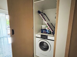 Een kleine wasruimte met een wasmachine, een droogrek en wasmiddel.