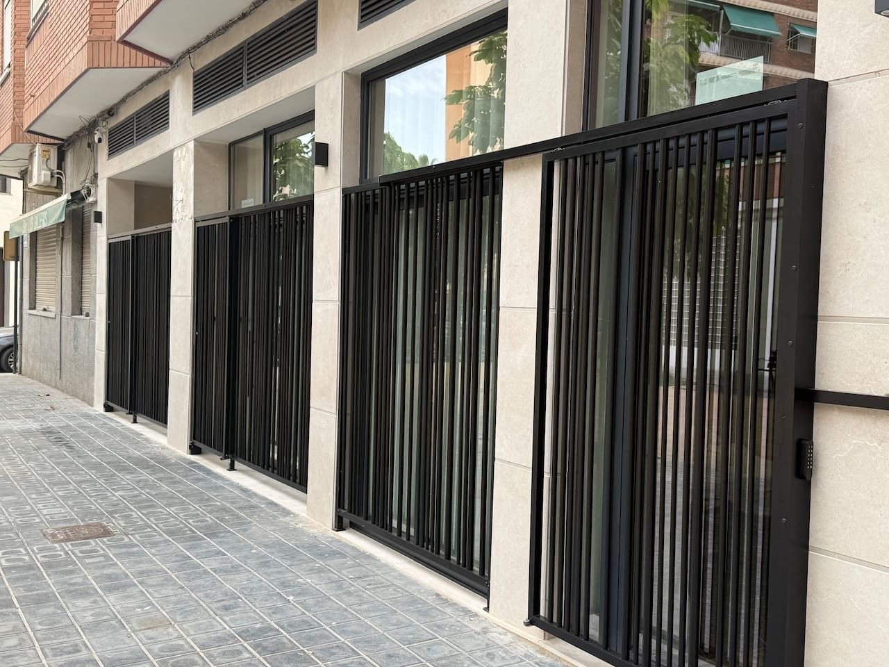 Une façade moderne avec une grille en métal, un trottoir dallé et un mur en briques.