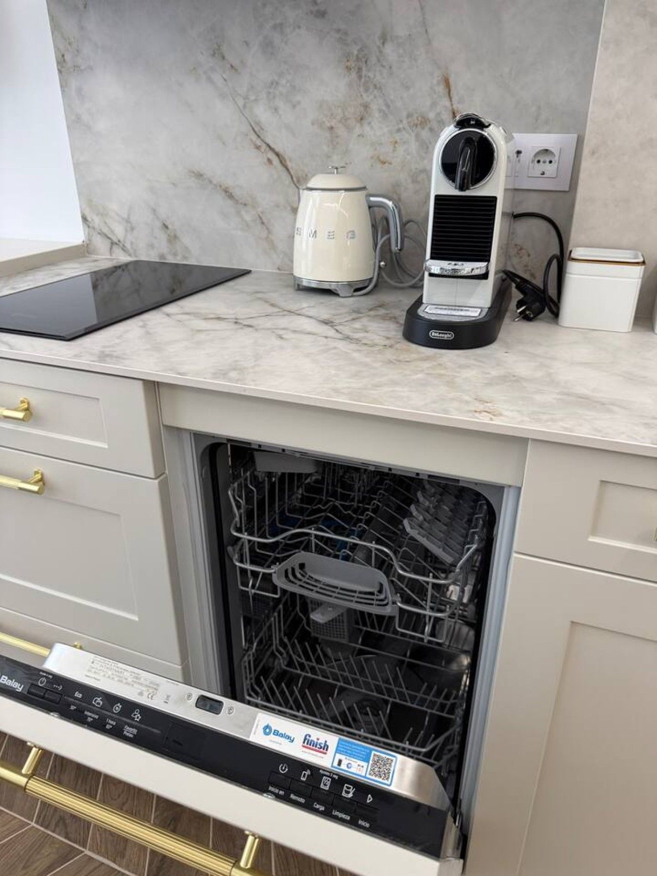 Une cuisine équipée d’un lave-vaisselle encastré, d’une machine à café et d’une tablette posée sur le plan de travail.