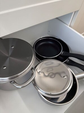 Een keuken met roestvrijstalen kookgerei, inclusief pannen en potten.