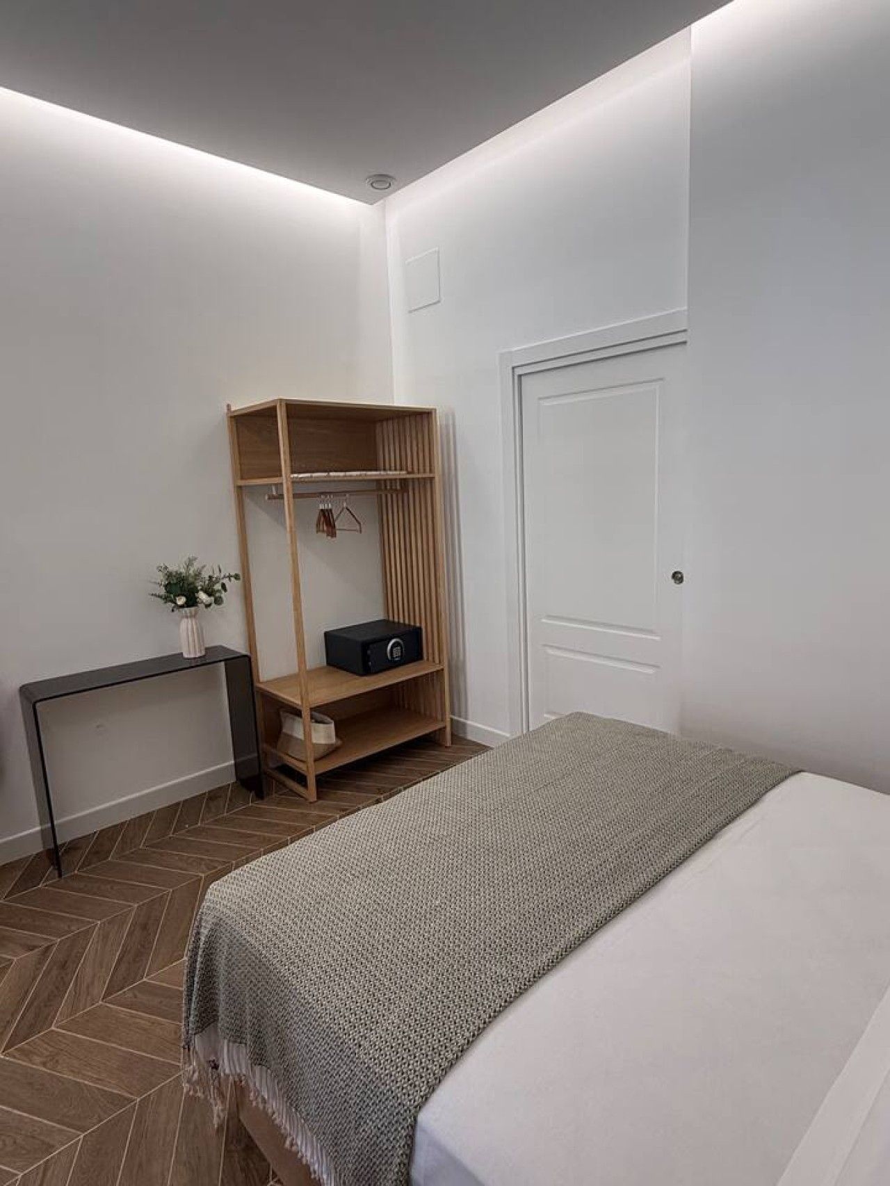 Une chambre à coucher comprenant un lit, une armoire en bois, une table de chevet et un radiateur.