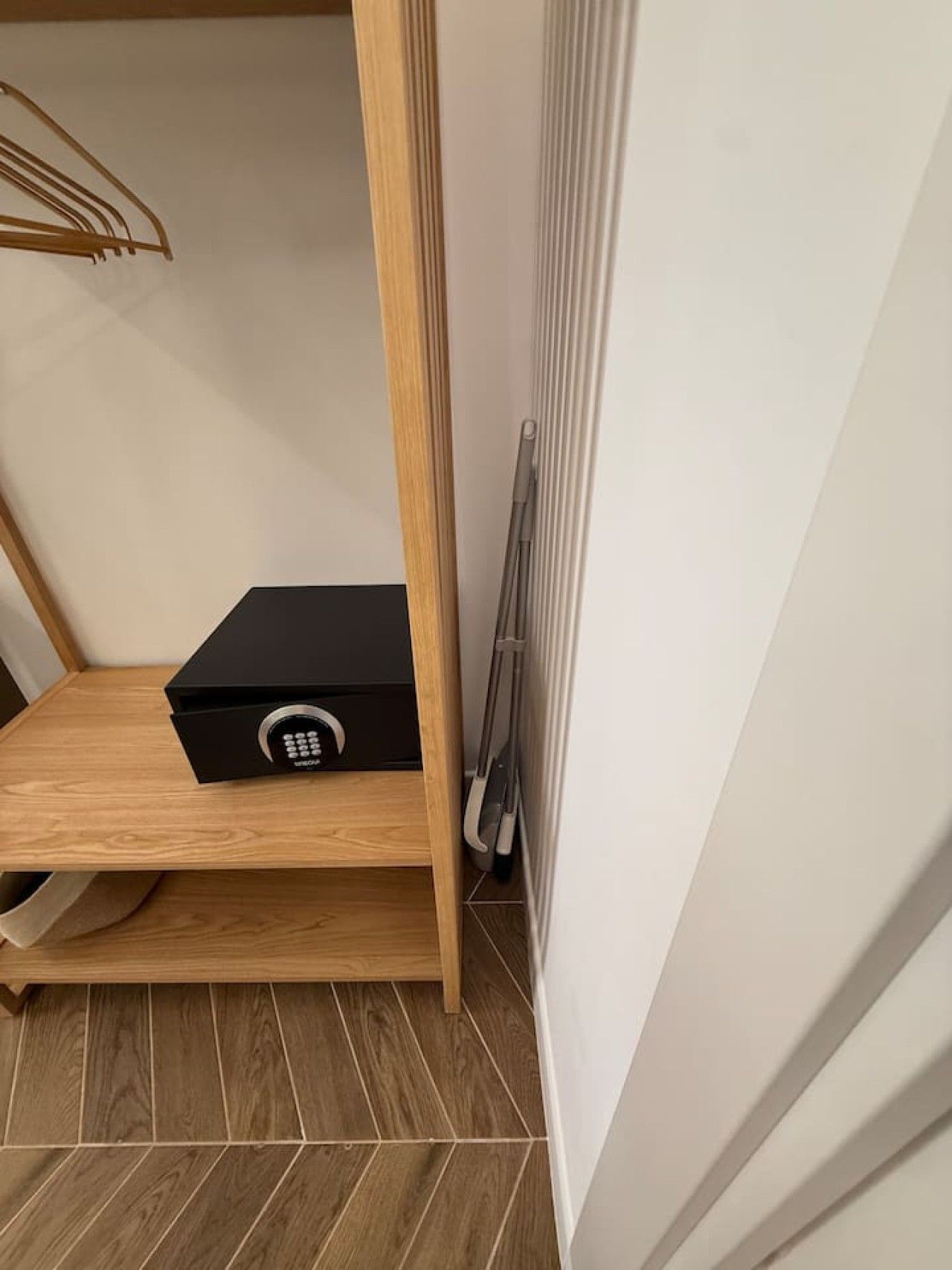 Eine Raumecke mit einem Holzregal, einem schwarzen elektronischen Gerät und einer Heizung.