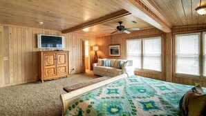A room with a bed, a TV, a wooden cabinet, a ceiling fan, and windows with blinds. - 4BR Beach House w/ Covered Porches, Game Room & Shared Creek Dock Access (Pawleys Island)