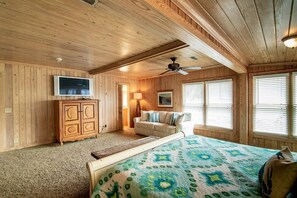 A room with a bed, a TV, a wooden cabinet, a ceiling fan, and windows with blinds. - 4BR Beach House w/ Covered Porches, Game Room & Shared Creek Dock Access (Pawleys Island)