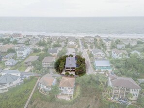 Un barrio residencial con casas, un edificio central con porche y vista al océano.