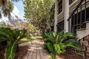 A pathway leading to a building with a brick wall and a window. - 4BR Beach House w/ Covered Porches, Game Room & Shared Creek Dock Access (Pawleys Island)