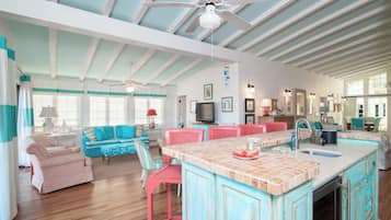 A spacious living area with a large island, a kitchen with a sink, and a dining area with red chairs.