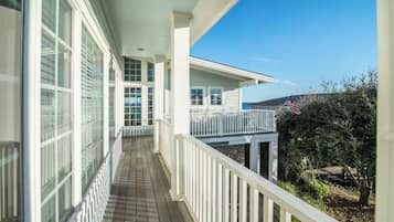 A covered balcony with a view of the ocean, white railings, and a small American flag.