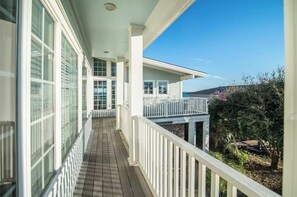 Un balcon fermé offrant une vue sur l’océan, avec des balustrades blanches et un petit drapeau américain.