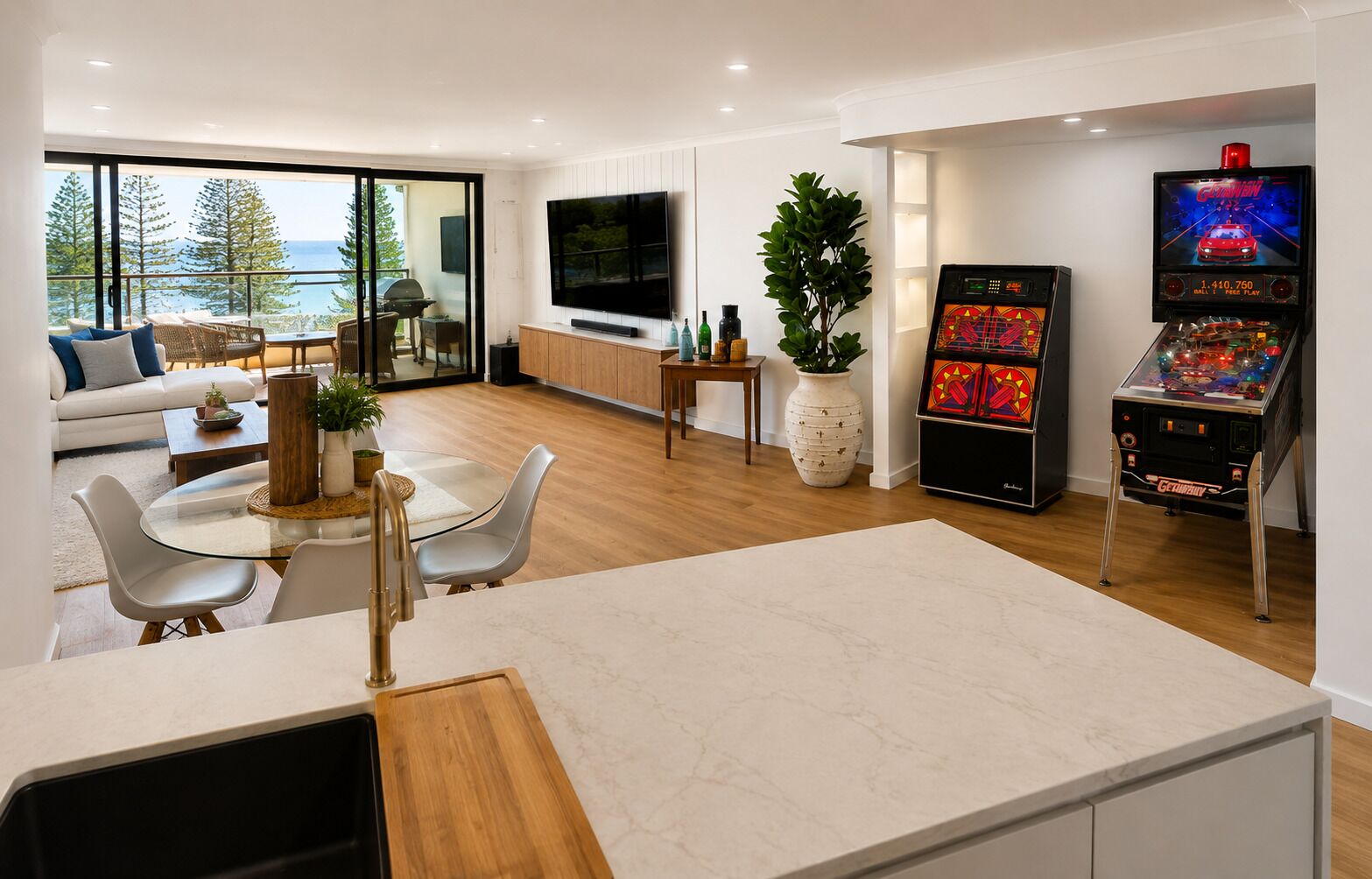 A modern living space with a kitchen area, dining table, and a large TV screen.