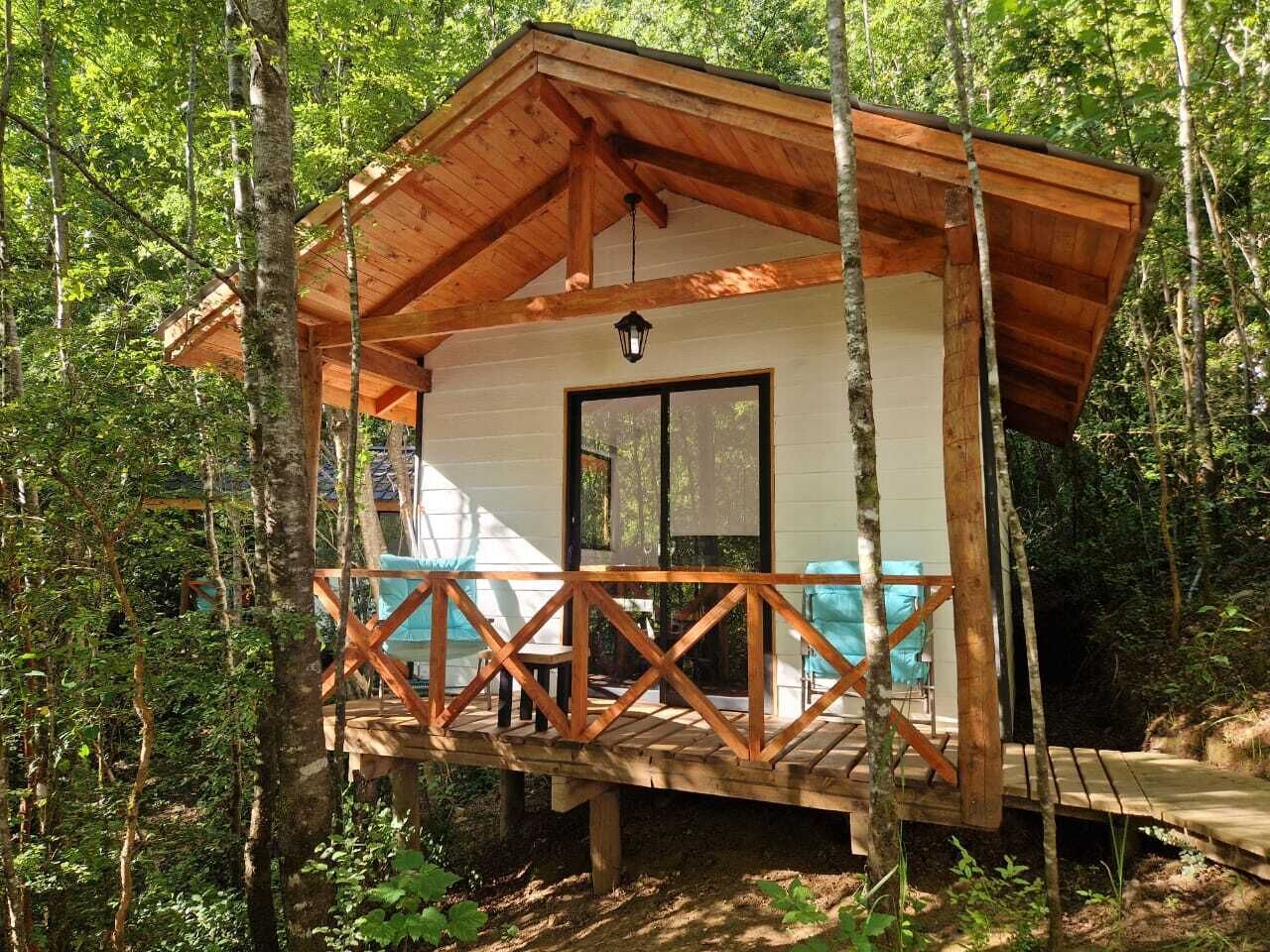 Une cabane en bois dotée d’un balcon, entourée d’arbres.