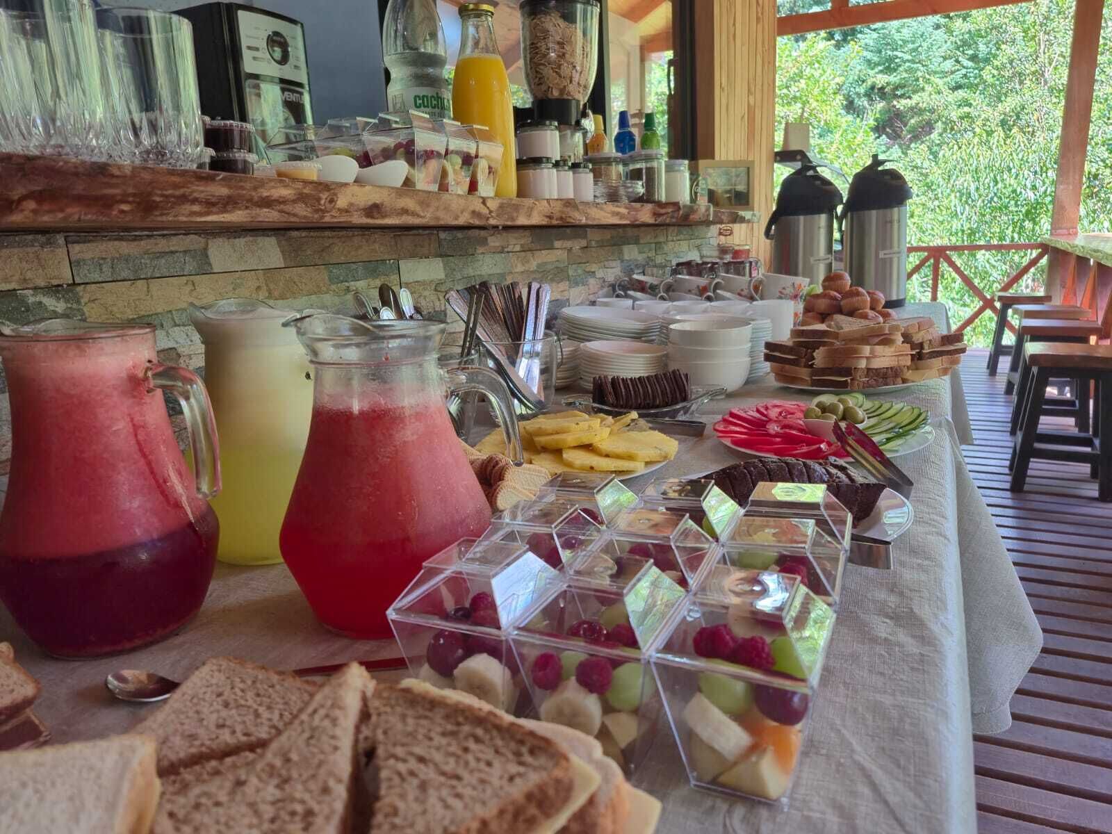 Noutopöytä, jossa on tarjolla monenlaista ruokaa ja juomaa, kuten mehuja, hedelmiä ja voileipiä.