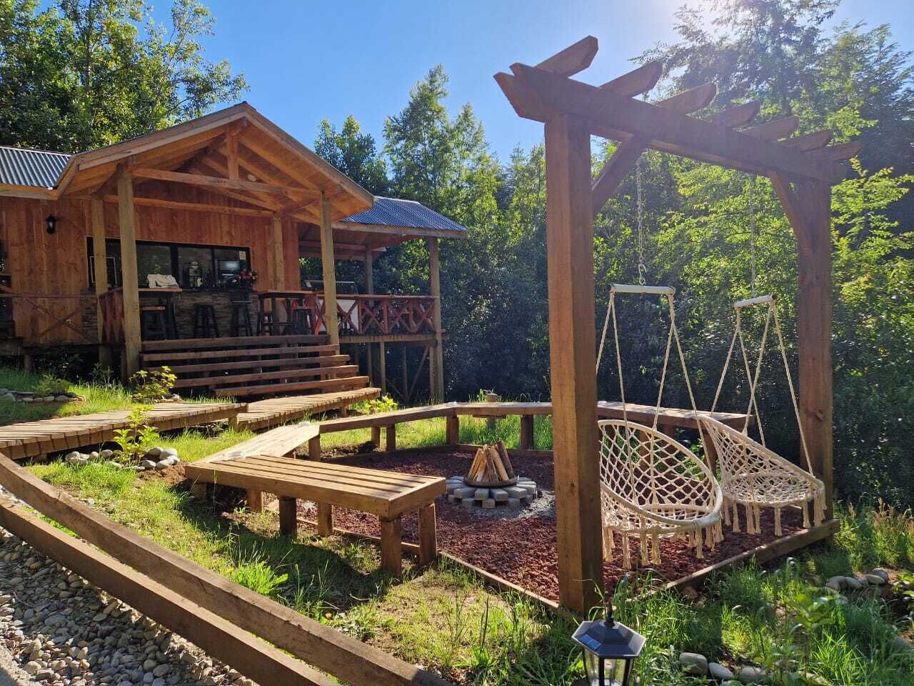 A wooden cabin with a covered porch, outdoor seating, and a swing set.