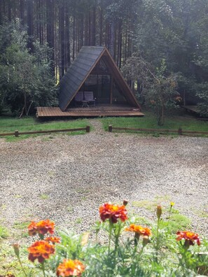 A triangular wooden cabin with a glass front, surrounded by a gravel path and greenery. - Ecos del Manantial (Villarrica)