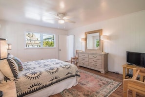 Ein Schlafzimmer mit Bett, Kommode, Fernseher und Deckenventilator.