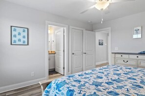 A bedroom with a bed, a ceiling fan, and a door leading to a bathroom. - New Ocean View Beach Home | 3-Min Walk to Litchfield Beach & Resort Amenities (Pawleys Island)
