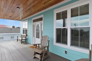 A covered porch with wooden flooring, a bench, and a Adirondack chair. - New Ocean View Beach Home | 3-Min Walk to Litchfield Beach & Resort Amenities (Pawleys Island)