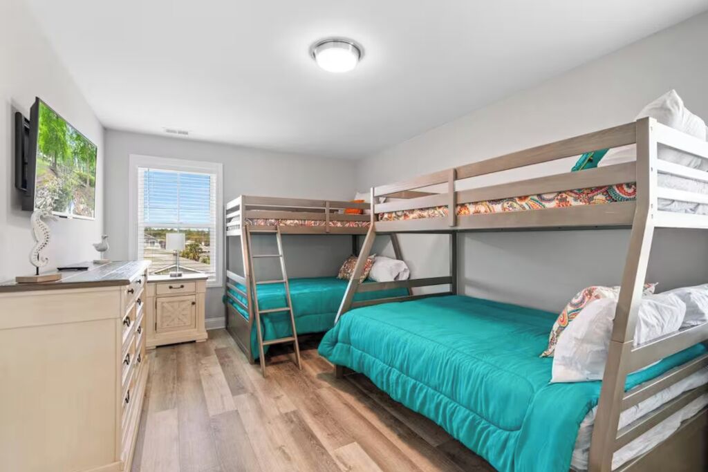 Quarto com beliche, escrivaninha e janela.