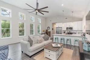 A modern kitchen with white cabinets, a central island, and bar stools. - Family-Friendly Coastal Retreat Near the Beach w/ Pools, Golf & Bike Trails (Pawleys Island)