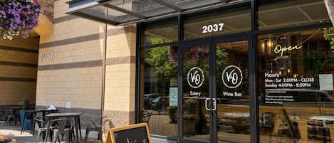 Exterior de un restaurante llamado 'Vino & Wine Bar' con un letrero que indica que es un restaurante Riverstone.