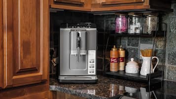 Una cucina con un frigorifero Bosch, una macchina per il caffè e uno scaffale con barattoli e condimenti.