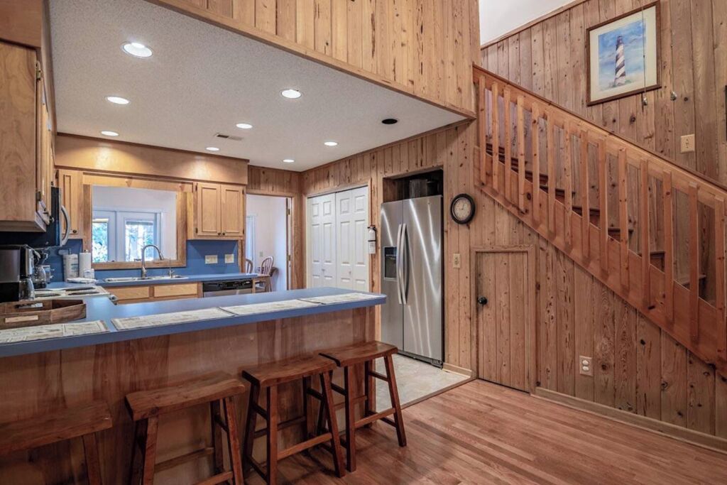 Eine Küche mit Holzwänden, einem Edelstahl-Kühlschrank und einer Holztreppe.