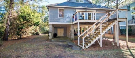 A two-story house with a covered porch and a wooden staircase leading to the upper level.