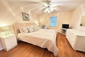 Een slaapkamer met een bed, een bureau, een stoel, een televisie en een dressoir.