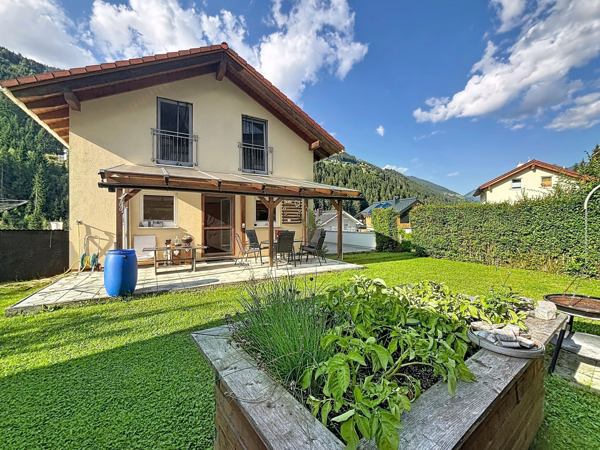 A two-story house with a patio, a barbecue grill, and a view of the surrounding hills.