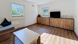 Ein modernes Wohnzimmer mit einer Couch, einem Couchtisch, einem Fernseher und Holzschränken.